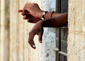 Hands reaching out from prison bars (c) John Woodworth