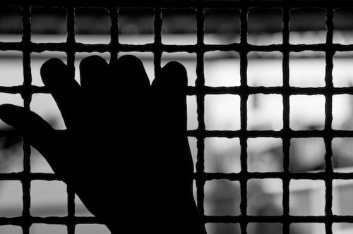 Freedom - image of a hand on cage, fingers on prison bars