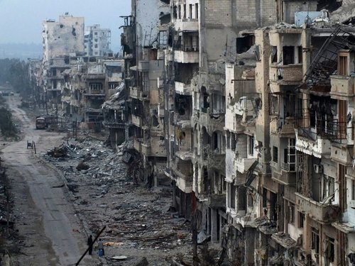 189500_people_stand_on_a_street_lined_with_damaged_buildings_in_the_besie_lgXUaeB.jpg