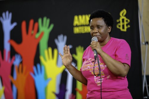Woman holding her hand up at an Amnesty event for the International Day Of The Girl Child Celebrations