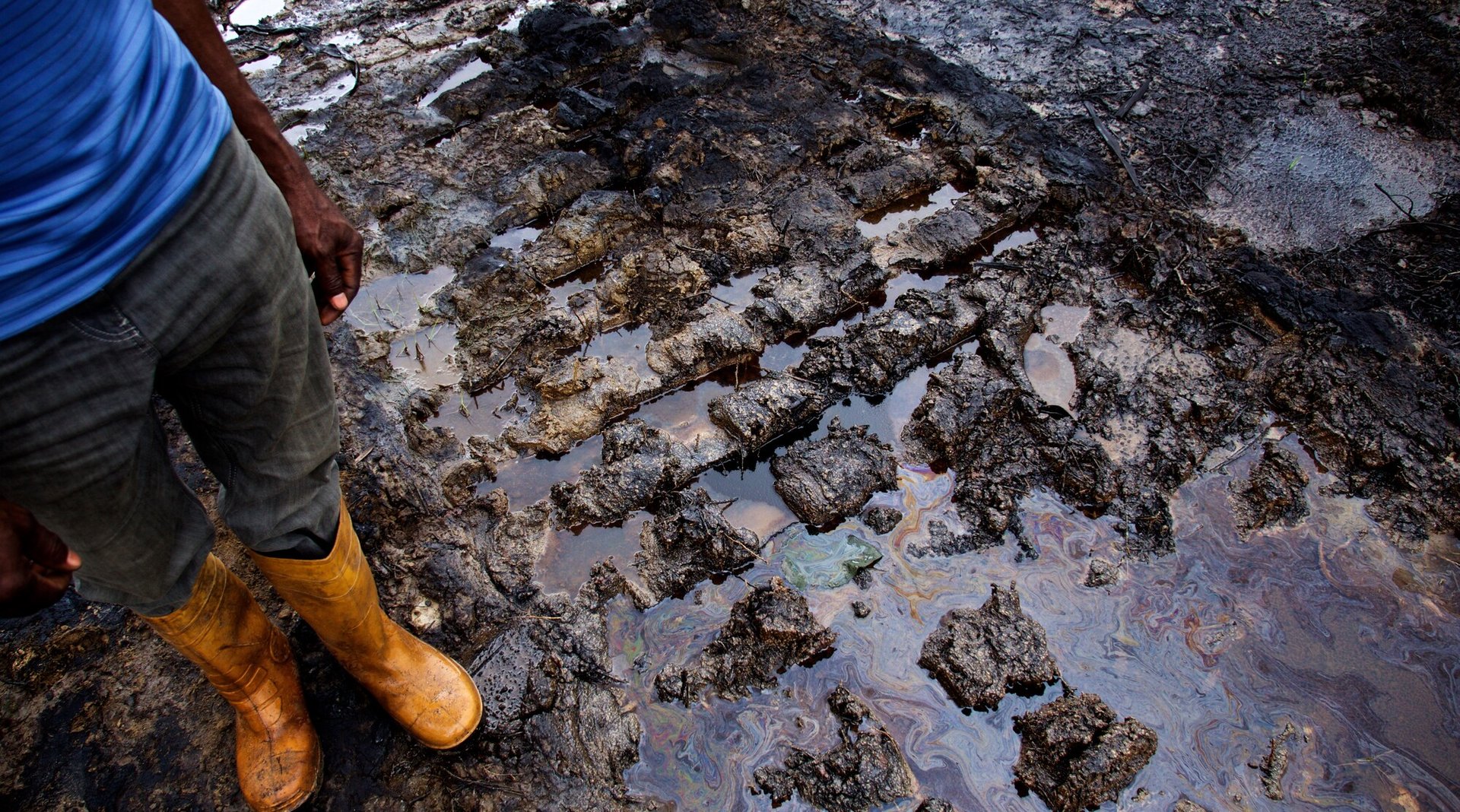 Person stands next to unremediated oil spill at Kegbara-Dere (K-Dere) community in Rivers State, Niger Delta, Nigeria, 2015