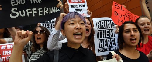 Refugee advocates shout slogans as they protest