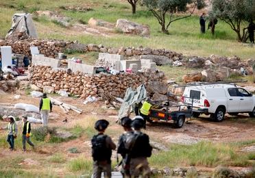 Israeli soldiers stand guard as Israeli workers remove a tent that was pitched near the Israeli settlement of Susya on March 28, 2018 after its resident Palestinian family was warned to evacuate.
