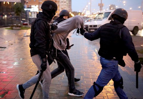 Three armed police detain an unarmed, peaceful protester in Belarus