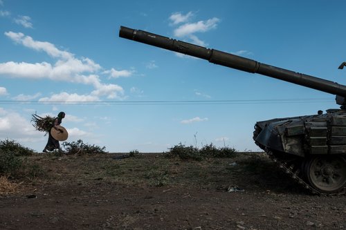 A woman carrying crops walks next to an abandoned tank belonging to Tigrayan forces south of the town of Mehoni, Ethiopia, on December 11, 2020. The town of Mehoni, located in Southern Tigray, experienced shelling resulting in civilian deaths and injured people. (Photo by EDUARDO SOTERAS / AFP) (Photo by EDUARDO SOTERAS/AFP via Getty Images)