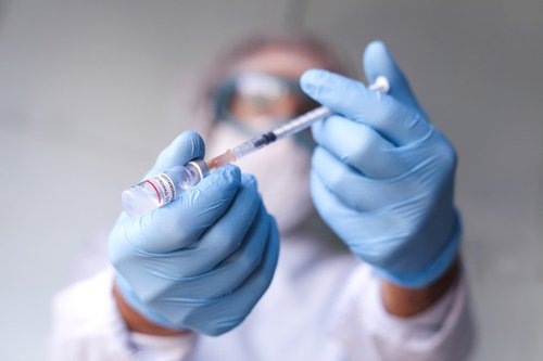 Clinician holds syringe and vial of vaccine