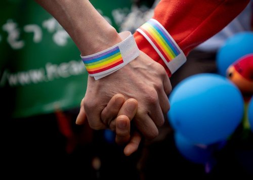 Two people hold hands in solidarity with LGBTQ+ rights