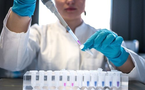Female scientist in laboratory researches Covid vaccine, using a pipette and test tube