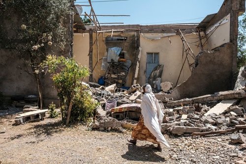 A woman walks amongst the ruins of a house in the midst of the Tigray conflict