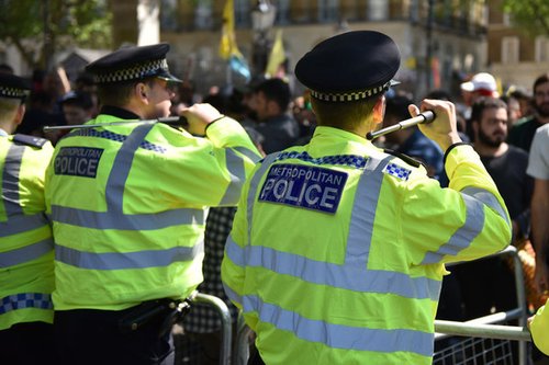 Police officers stand with their batons raised as anti-Erdogan protesters stage a demonstration outside Downing Street