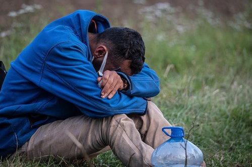 Afghan asylum seeker is pictured distressed, sitting with his head in his hands at the Poland-Belarus border. Image taken last month.