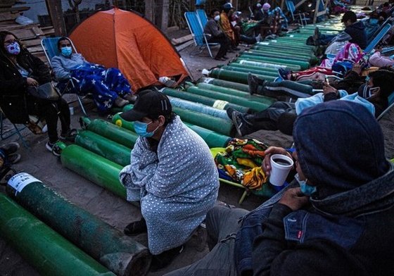 People camp as they wait to refill empty oxygen cylinders in Villa El Salvador, on the southern outskirts of Lima, on February 25, 2021, amid the COVID-19 coronavirus pandemic