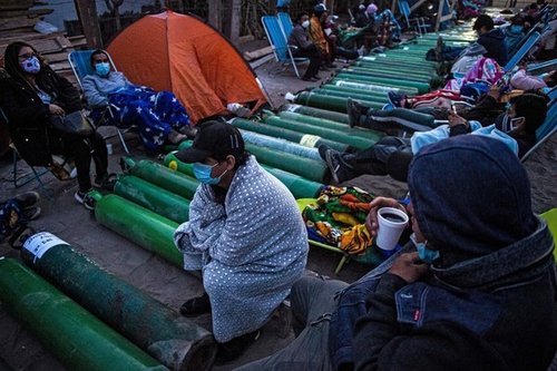 People camp as they wait to refill empty oxygen cylinders in Villa El Salvador, on the southern outskirts of Lima, on February 25, 2021, amid the COVID-19 coronavirus pandemic