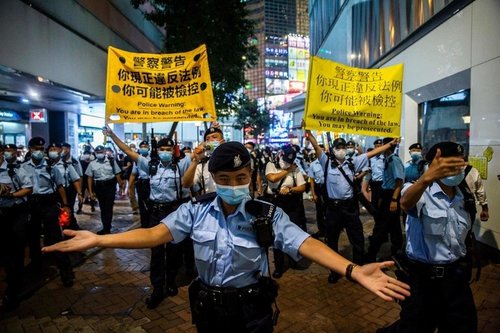 Hong Kong police in foreground shut down Tiananmen Square anniversary vigil - protesters hold placards in background