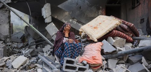 Palestinian woman sat on rubble crying - Gaza