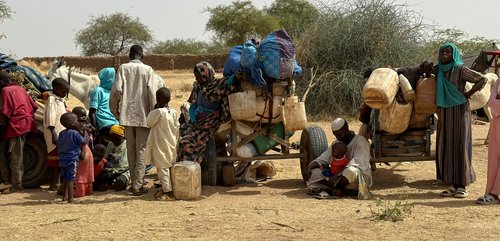 A group of men, women and children on the move with their belongings, displaced by RSF attacks on their Internally Displaced Persons camp.