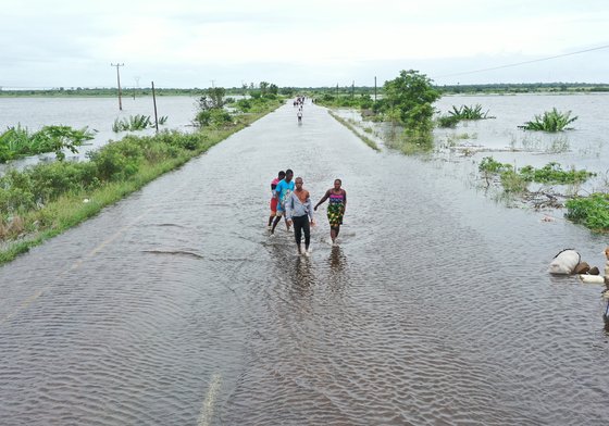 Aerial view of residents wading through floodwater to cross a road in Mozambique.