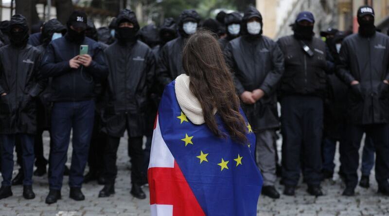 Police officers stand guard as protesters, staging protest, endeavor to breach the security perimeter of the Georgian Parliament