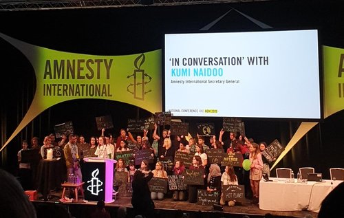Image shows climate activists on stage at the Amnesty AGM with Kumi Naidoo
