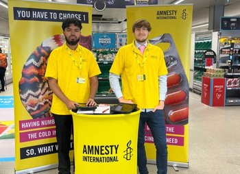 Amnesty fundraisers standing at a fundraising station in a supermarket