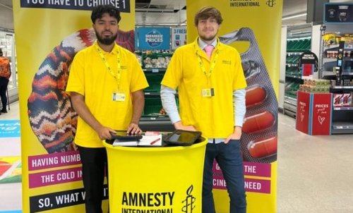 Two Amnesty International UK fundraisers in a supermarket signing people up to donate to Amnesty