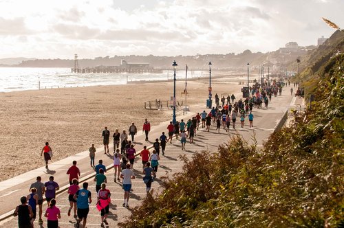 Hundreds of people run alongside a beautiful coastal scene.