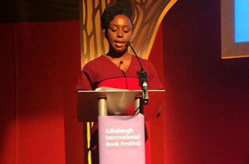 The picture shows an author standing at a podium speaking.