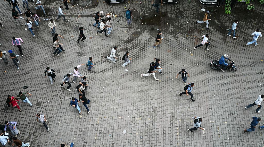 Cockroach Janta Party (CJP) supporters run as police fire tear gas shells to disperse them