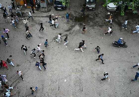 Cockroach Janta Party (CJP) supporters run as police fire tear gas shells to disperse them
