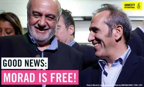 Morad stands in a group of people and smiles directly at the camera.