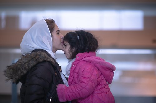 Woman kisses forehead of child