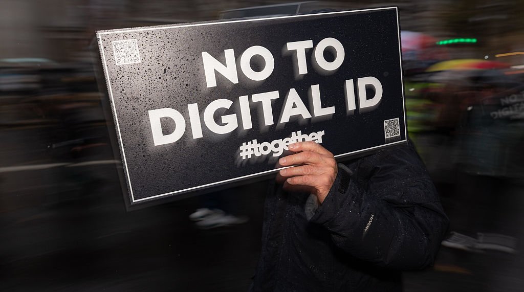 A demonstrator holds a placard reading "No to Digital ID...