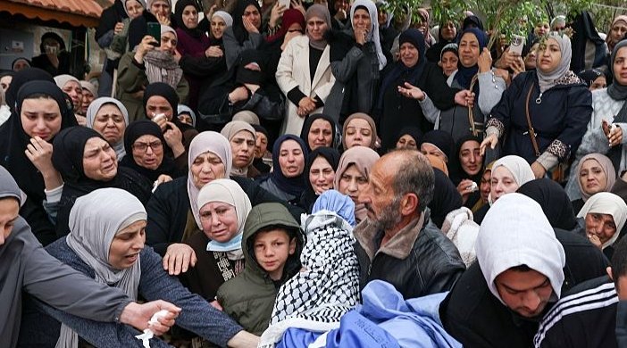 A family member lifts the body of Mohammed Bani Odeh, one of the two boys killed along with their parents by Israeli soldiers while in their vehicle, during their funeral in the Israeli-occupied West Bank town of Tammun on March 15, 2026.