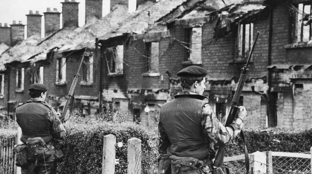 British soldiers stand on guard over houses in Belfast during the Troubles