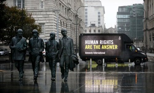 Image of a street with a truck that has a asign reading 'Human rights are the answer'