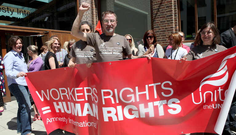 Activists and Amnesty staff holding a banner "Worker's rights = Human Rights"