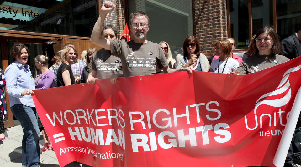 Activists and Amnesty staff holding a banner "Worker's rights = Human Rights"
