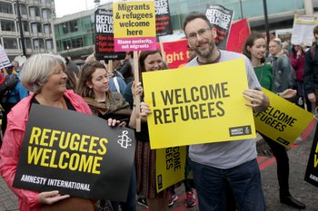 Woman holding sign saying Refugees Welcome here at a protest