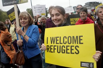 Protests holding a sign that says I welcome refugees