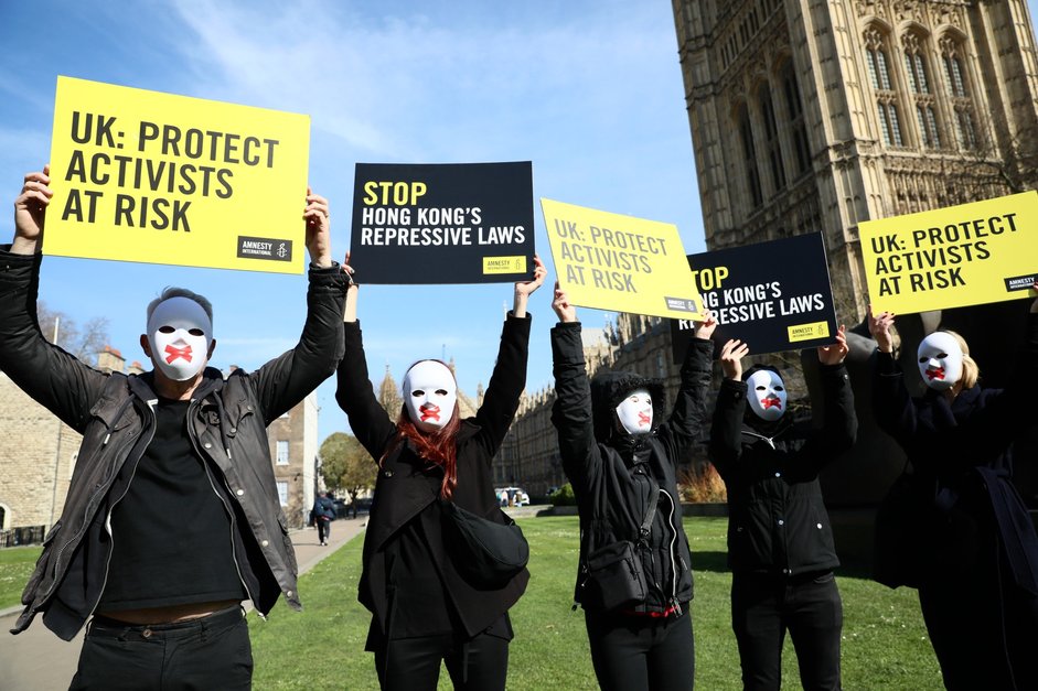 Hong Kong activists holding placards outside Westminster, demanding UK authorities to protect activists.