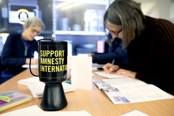 Amnesty fundraisers at a desk with a donation pot