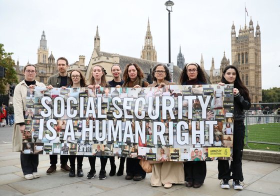 A number of protestors holding a banner that says Social Security is a human Right