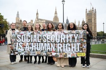 A number of protestors holding a banner that says Social Security is a human Right