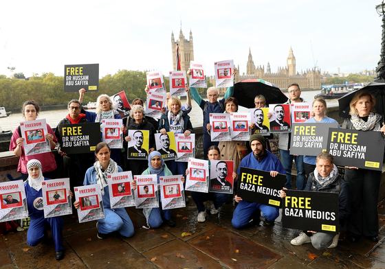 Medics wearing scrubs and activists holding placards reading “Free Gaza Medics”, “Free Dr Hussam Abu Safiya”, “Stop Arming Israel” the protesters stood against the backdrop of Parliament.