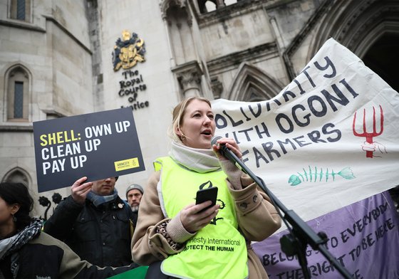 An Amnesty International staff member stands outside the Royal Courts of Justice delivering a speech demanding Shell pay to clean up their oil spill in the Niger Delta.
