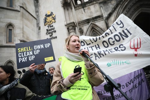 An Amnesty International staff member stands outside the Royal Courts of Justice delivering a speech demanding Shell pay to clean up their oil spill in the Niger Delta.