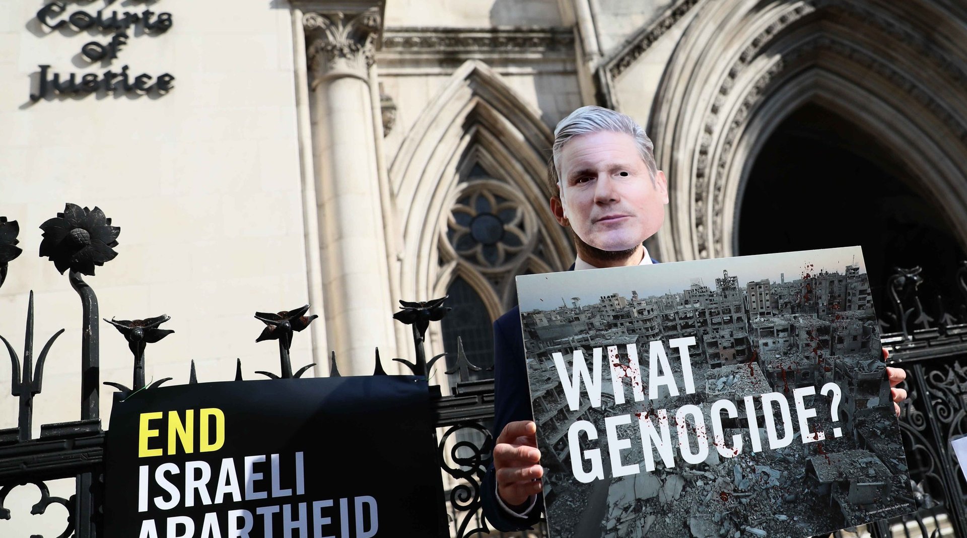 Masked Keir Starmer holding placard reading "What genocide?"