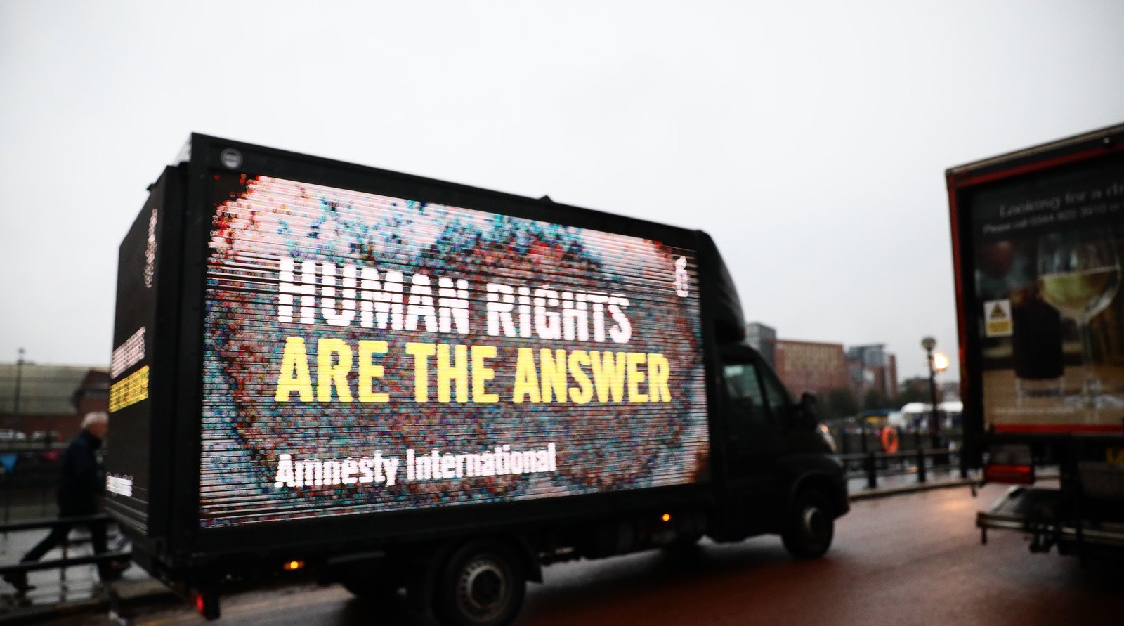 A mobile electronic billboard on the back of a van says 'Human rights are the answer'