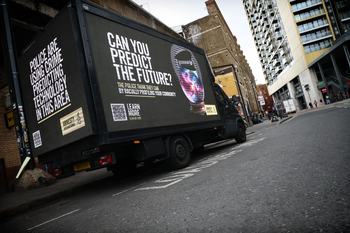 Truck parked on a road with a banner on all sides promoting Amnesty's predictive policing campaign.
