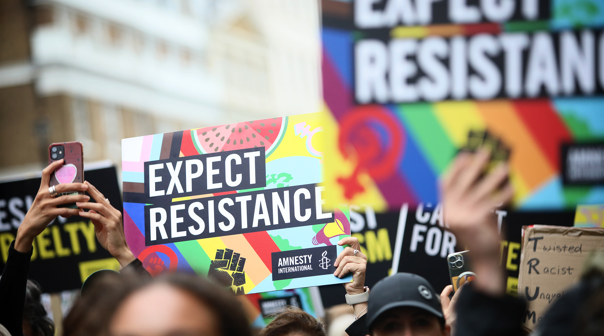 Protesters holding Amnesty UK 'Expect Resistance' placards at a march in London.